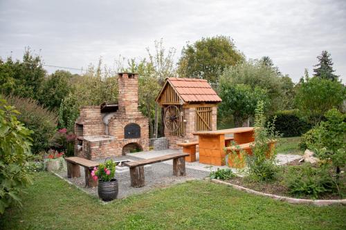 a garden with a brick fireplace and a bench and a house at Rózsa Porta in Zengővárkony