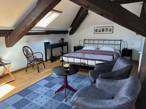 a bedroom with a bed and two chairs and a table at Villa Moncoeur in Remiremont