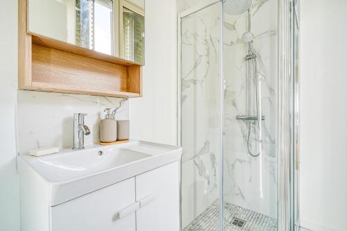 ein weißes Bad mit einem Waschbecken und einer Dusche in der Unterkunft Appartement Parisien Porte d'Ivry in Ivry-sur-Seine