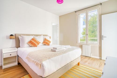 ein weißes Schlafzimmer mit einem großen Bett und einem Fenster in der Unterkunft Appartement Parisien Porte d'Ivry in Ivry-sur-Seine