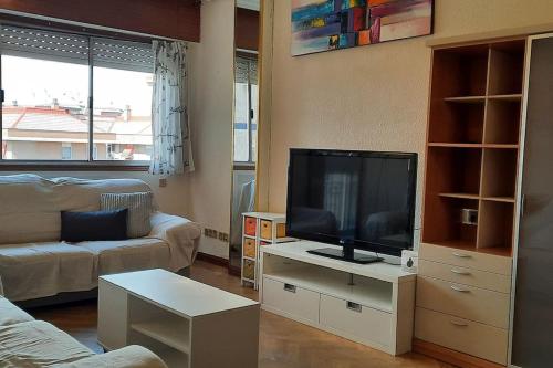 Una sala de estar con un televisor de pantalla plana sobre una mesa. en Piso amplio, iluminado y muy bien comunicado, en Madrid