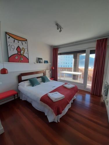ein Schlafzimmer mit einem großen Bett und einem großen Fenster in der Unterkunft Muskaria Espectacular 1ª Línea Playa-piscina by Egona in Zarautz