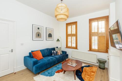 a living room with a blue couch and a table at Spacious 4BR 3-Storey Townhouse in Lively Deptford in London
