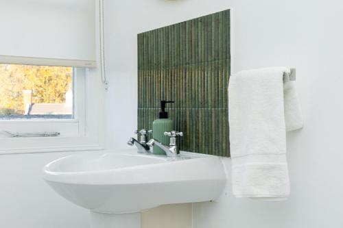 a white bathroom with a sink and a window at Spacious 4BR 3-Storey Townhouse in Lively Deptford in London