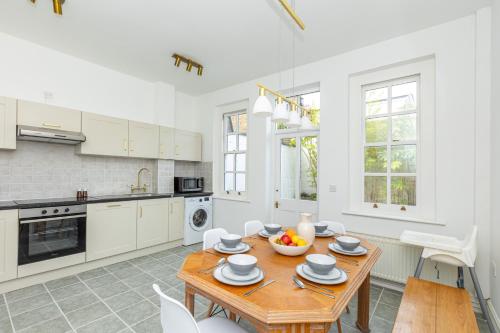 a kitchen with a wooden table and white cabinets at Spacious 4BR 3-Storey Townhouse in Lively Deptford in London