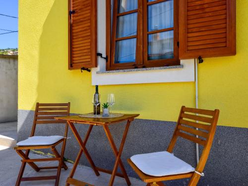 2 Stühle und ein Tisch vor einem gelben Haus in der Unterkunft Apartment Val-1 by Interhome in Sveti Juraj