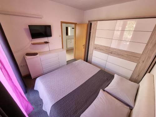 una piccola camera da letto con un letto e una televisione di NIKO LUX Apartment with Jacuzzi only 70m from the beach a Dramalj