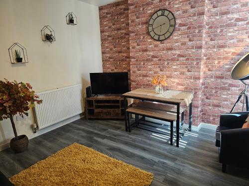 a living room with a table and a brick wall at Fife House - 4 Bedroom Contractor Accommodation in Derby in Derby