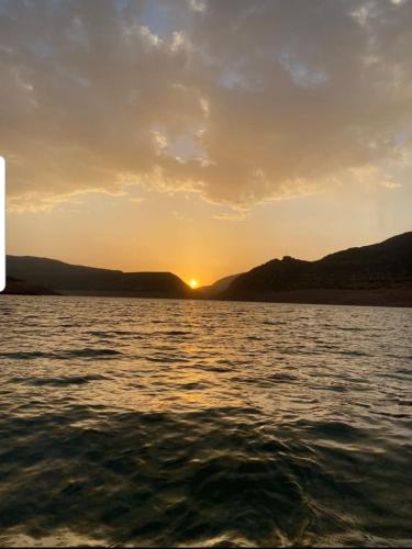 a sunset over a body of water with mountains at Le Figuier du Lac Bin elouidane in Bine el Ouidane
