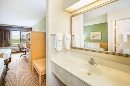 a hotel bathroom with a sink and a mirror at Ramada by Wyndham Spirit Lake/Okoboji in Spirit Lake