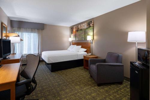 um quarto de hotel com uma cama, uma secretária e uma cadeira em Days Inn & Suites by Wyndham Madison em Madison