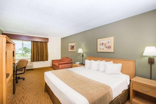 a hotel room with a bed and a chair at Ramada by Wyndham Spirit Lake/Okoboji in Spirit Lake