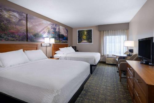a hotel room with two beds and a flat screen tv at Days Inn & Suites by Wyndham Madison in Madison