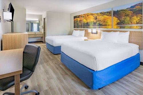 a hotel room with two beds and a desk at Days Inn by Wyndham Spartanburg Waccamaw in Southern Shops