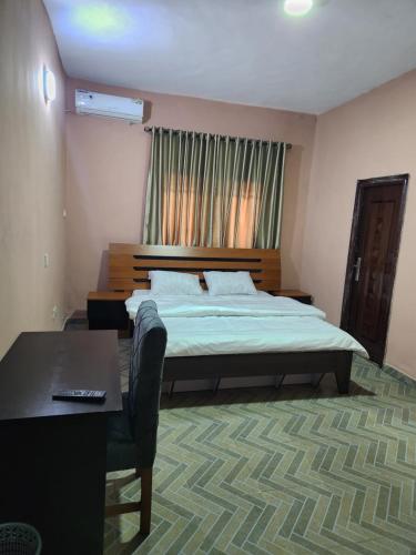 a bedroom with a bed and a table and a desk at See Good Guest House Enimarire in Sangotedo