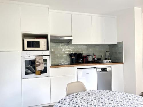 - une cuisine blanche avec des placards blancs et une table dans l'établissement Le Rocher Trouville, à Trouville-sur-Mer