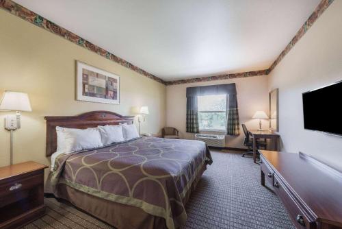 a hotel room with a bed and a flat screen tv at Super 8 by Wyndham Fort Worth North/Meacham Blvd in Fort Worth