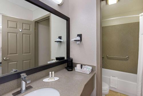 a bathroom with a sink and a mirror and a toilet at Days Inn by Wyndham Savannah in Savannah