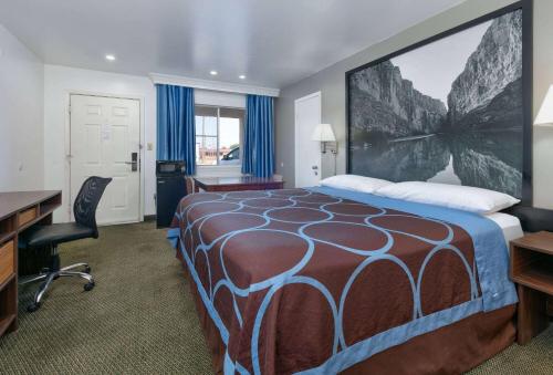 a hotel room with a bed and a desk at Super 8 by Wyndham Vernon in Vernon