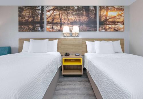 ein Hotelzimmer mit 2 Betten und einem gelben Tisch dazwischen. in der Unterkunft Days Inn by Wyndham Greenville MS in Greenville