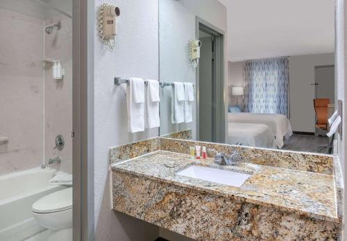 a bathroom with a sink and a bathroom with a bed at Days Inn by Wyndham Greenville MS in Greenville