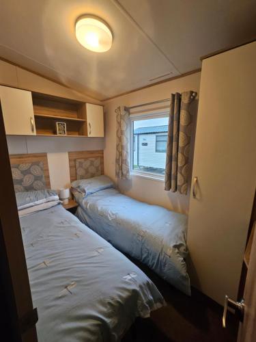 two beds in a small room with a window at KMH Caravans at Flamingo Land in Kirby Misperton