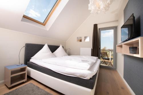 a bedroom with a bed and a tv and a window at Ostsee - Appartement Nr 25 "Godetied" im Strand Resort in Heiligenhafen