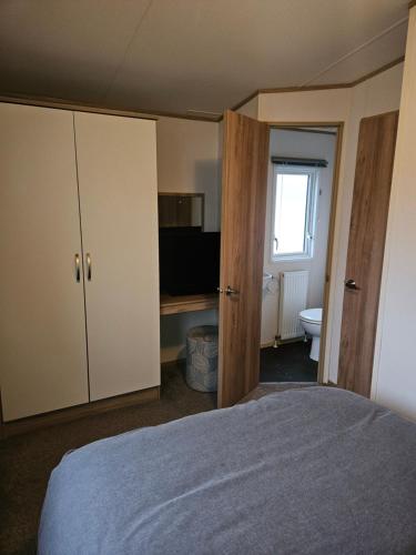 a bedroom with a bed and a bathroom with a window at KMH Caravans at Flamingo Land in Kirby Misperton