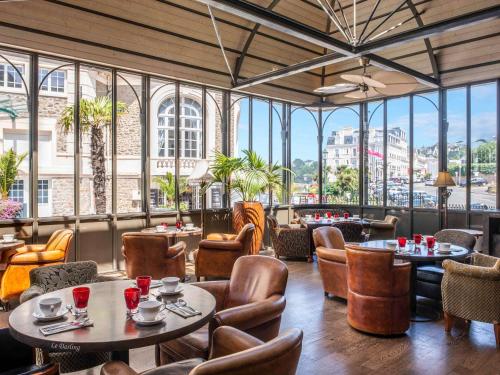 - un restaurant avec des tables, des chaises et de grandes fenêtres dans l'établissement Royal Emeraude Dinard - MGallery, à Dinard