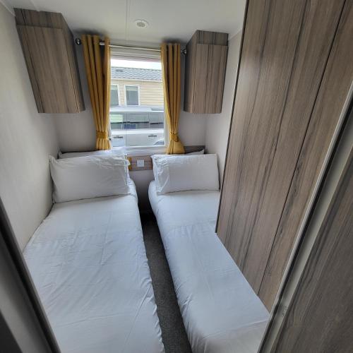 two beds in a small room with a window at KMH Caravans at Flamingo Land in Kirby Misperton