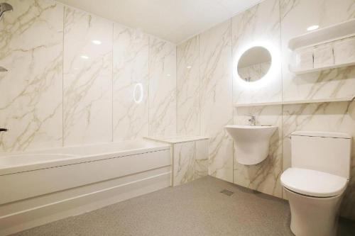 a white bathroom with a toilet and a sink at Urban Stay in Cheonan