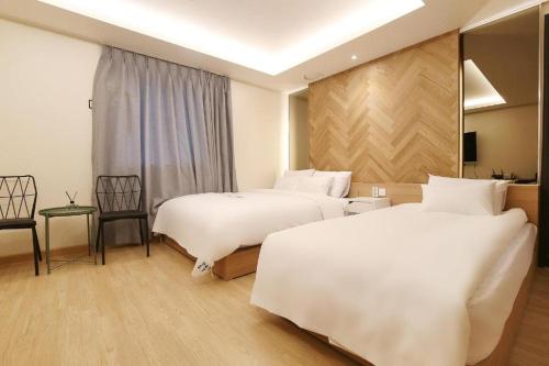 a hotel room with two beds and a table and chairs at Urban Stay in Cheonan