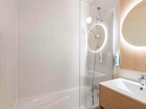 a white bathroom with a shower and a sink at Aparthotel Adagio Access Paris La Villette in Paris
