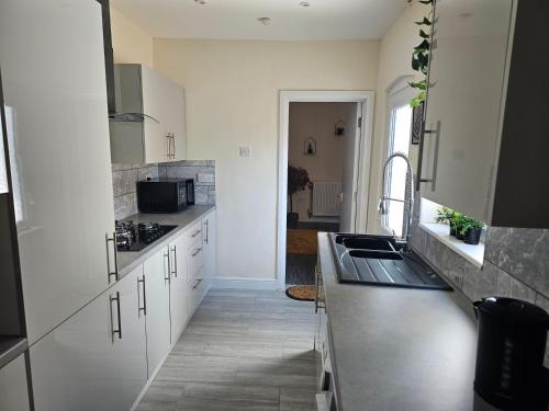 a kitchen with white cabinets and a sink at Fife House - 4 Bedroom Contractor Accommodation in Derby in Derby
