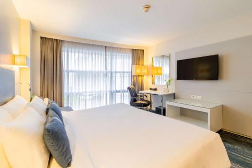 una camera d'albergo con un grande letto e una TV di Best Western Sukhumvit 20 a Bangkok