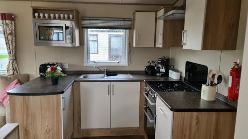 a small kitchen with white cabinets and a sink at KMH Caravans at Flamingo Land in Kirby Misperton