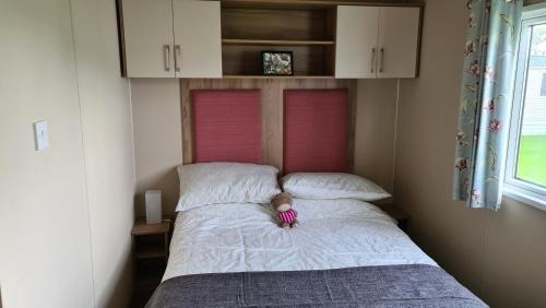 a teddy bear sitting on a bed in a bedroom at KMH Caravans at Flamingo Land in Kirby Misperton