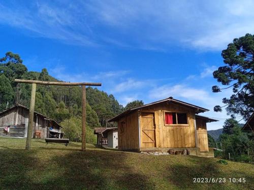 uma pequena casa de madeira numa colina com um banco em Rancho Toa-toa próximo a Gonçalves MG em Sapucaí-Mirim