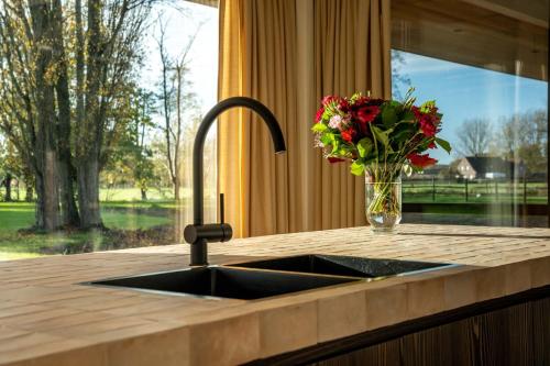 um lavatório de cozinha com um vaso de flores ao lado de uma janela em Equilodge 't Blommeke - Reconnect with nature em Bruges
