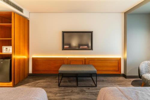 a room with a tv on a wall with a stool at Laghetto Stilo São Paulo in Sao Paulo
