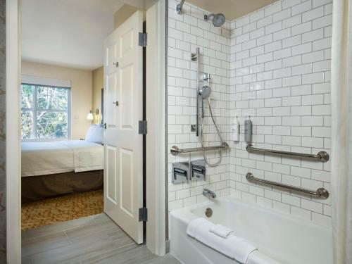 Homewood Suites by Hilton Newark Fremont في فريمونت: حمام مع حوض وغرفة نوم مع سرير