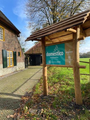 a sign in the grass in front of a building at Domestico Bed & Breakfast in Lage Mierde