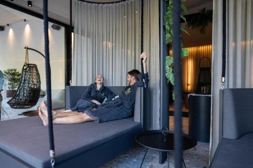 two people sitting on a couch with their arm in the air at Lifesteil Aparthotel in Umhausen