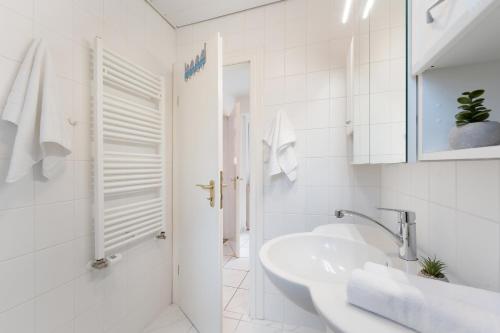 a white bathroom with a sink and a shower at Ferienhaus Schneider, Snieder's Hoeg in Grömitz