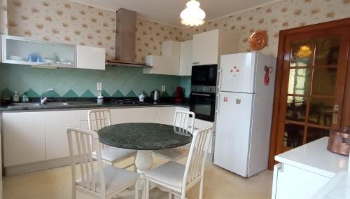 une cuisine avec une table et un réfrigérateur blanc dans l'établissement Maison au bord du lac, à Cagnac-les-Mines