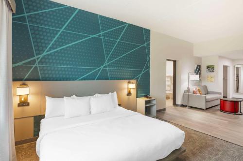 a bedroom with a white bed and a green wall at Comfort Suites in Bloomsburg