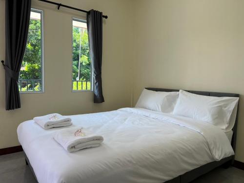 una camera da letto con un letto bianco e asciugamani di KP House Bueng Kan a Seka