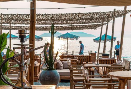 a beach bar with tables and chairs and people on the beach at Yacht Hotel in Vlorë