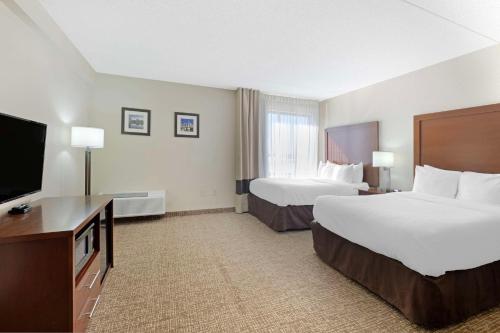 a hotel room with two beds and a flat screen tv at Comfort Inn & Suites in Wichita