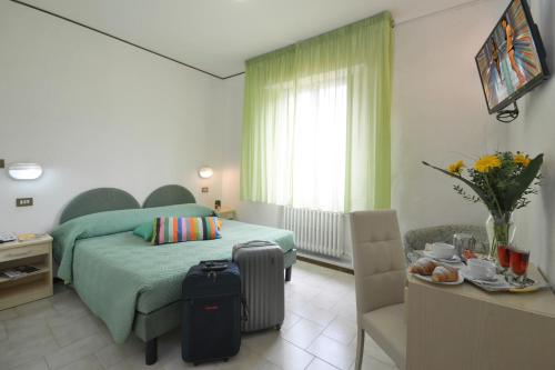 una camera con un letto e un tavolo con una valigia di Albergo Martini a Chianciano Terme